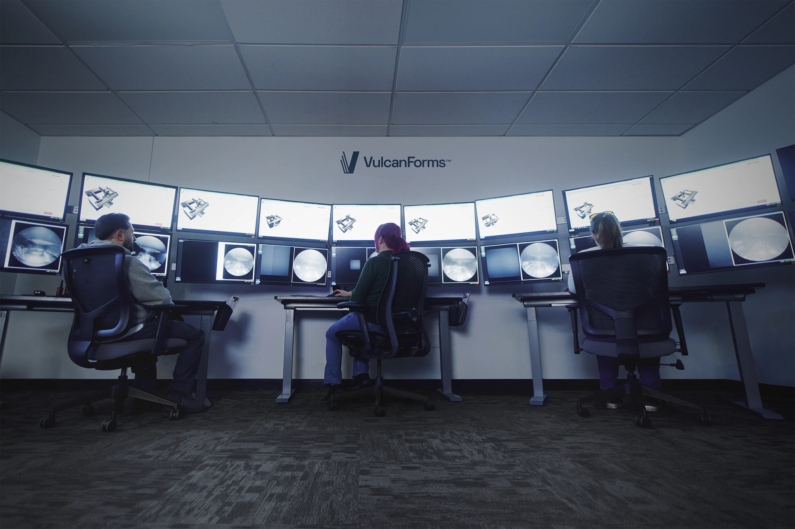 Three operators monitor multiple screens displaying digital metal manufacturing data at VulcanForms.