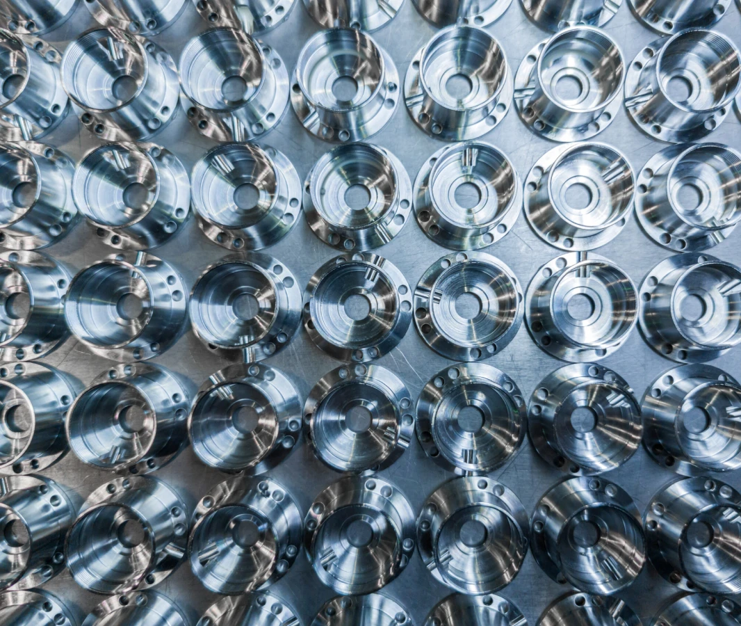 A close-up view of numerous precision-machined aluminum components arranged in a grid pattern.