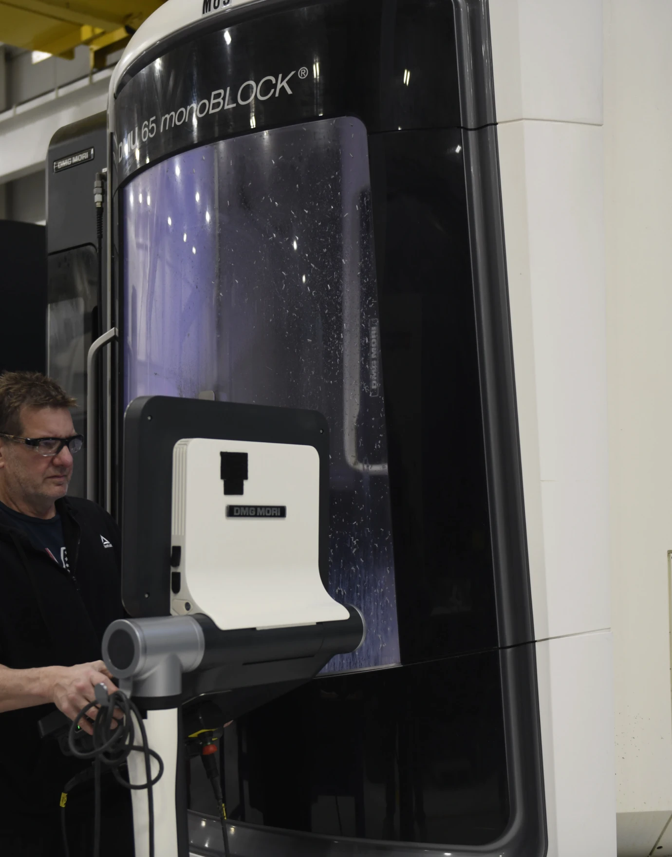 A technician operates a DMG MORI MU 65 monoBLOCK machining center in an aerospace manufacturing facility.